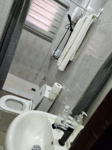 a bathroom with a white sink and a toilet at SBJ Place East Legon in Accra