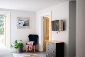 a bedroom with a tv and a blue chair at Cymyran Terrace in Holyhead +41 photos