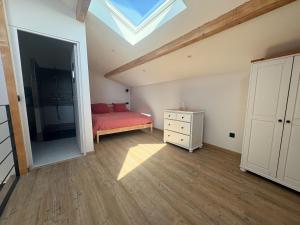 a bedroom with a red bed and a skylight at L'échappée verte in Chirens