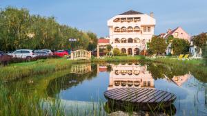 Ein großes Haus spiegelt sich in einem Wasserkörper wider in der Unterkunft Das-Schmidt Privathotel in Mörbisch am See