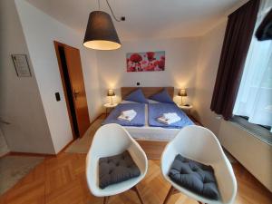 ein Schlafzimmer mit einem Bett und zwei weißen Stühlen in der Unterkunft Grüner Baum in Neckargerach