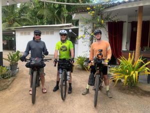 three men are posing with their bikes in front of a house at Paradise inn in Kamburagalla