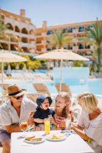 a group of people sitting at a table with food at Mirador Maspalomas by Dunas in Maspalomas