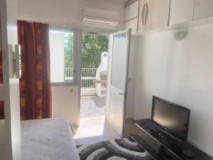 a room with a bed and a television and a balcony at Studio avec piscine et grande terrasse Parking gratuit Nice in Nice
