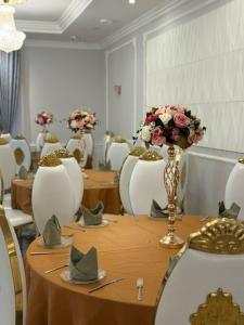a room with tables and chairs with flowers on them at Travel Plaza Hotel in Desborough
