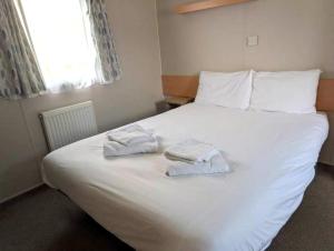 two towels on a white bed in a bedroom at Seashell Cove - 2 bedrooms sleeps 6 in Dymchurch
