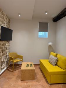 a living room with a yellow couch and a table at Corcyra Collection in Corfu