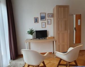 Ein Zimmer mit zwei weißen Stühlen und einem Computer auf einem Schreibtisch in der Unterkunft Grüner Baum in Neckargerach + 12 Fotos