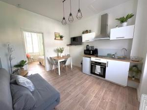 a living room with a couch and a kitchen with a table at Le Paisible - proche des Thermes in Chamalières