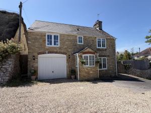 a large brick house with a white garage at Fisherbridge Cottage in Weymouth