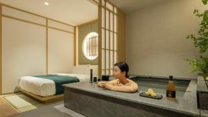a woman sitting in a bath tub in a bedroom at Anook Ryokan Hotel Suwon Ingye in Suwon