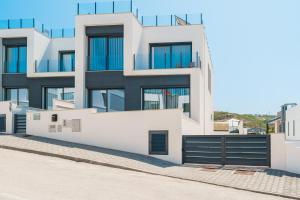 a white building with black doors and windows at Paradise Villa Sea - Signature by Paradise Portugal in Ribamar +46 photos