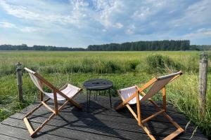 two chairs and a table on a wooden deck with a field at Dzika Jurta na Łebkach in Łebki