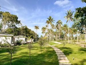 a garden with palm trees and a path at Cococreek Kohkood in Ban Khlong Mat