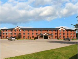 a large red brick building with a parking lot at Days Inn & Suites by Wyndham Des Moines Airport in Des Moines