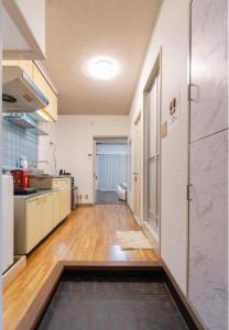 a kitchen with white cabinets and a wooden floor at Kasuga Good Place House in Kasugabaru