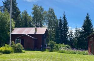 a red barn in a field next to a house at Bagarstugan in Älvdalen