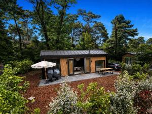 a small cabin with a patio and an umbrella at Huisje Mae in Nunspeet
