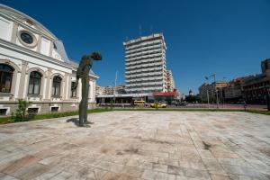a statue in the middle of a city with a building at Hotel Decebal in Bacău