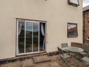 a patio with a table and chairs and a window at Flodden Apartment in Wooler