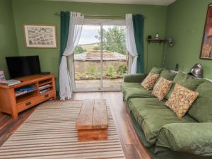 a living room with a green couch and a window at Flodden Apartment in Wooler