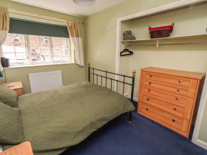 a bedroom with a bed and a dresser and a window at Flodden Apartment in Wooler