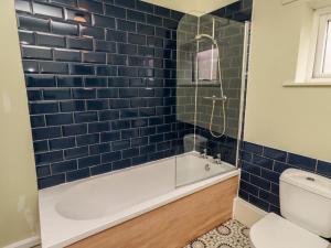 a blue tiled bathroom with a tub and a toilet at Flodden Apartment in Wooler +11 photos