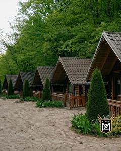 a row of cottages with a fence and trees at Resort Maja e Zezë in Gnjilane