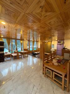 a large room with wooden ceilings and tables and windows at Gaunnie Valley - Jibhi in Jibhi