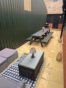 a patio with two picnic tables and a green fence at The Old Dairy Accommodation in Tillingham