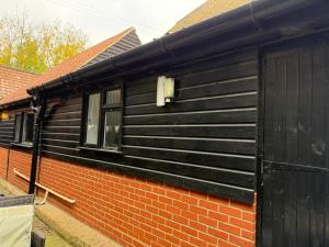 a black building with a window and a brick wall at The Old Dairy Accommodation in Tillingham