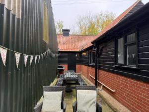 a patio with two chairs and a building at The Old Dairy Accommodation in Tillingham