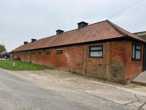 a brick building with a red roof on a street at The Old Dairy Accommodation in Tillingham