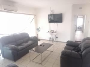 a living room with two couches and a tv at Royal Oasis in Mahikeng
