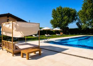 a chair and umbrella next to a swimming pool at Villa Monet in Castiglione di Ravenna
