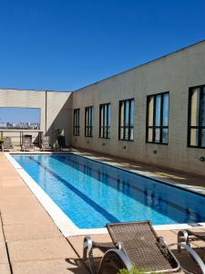 a swimming pool with chairs in front of a building at Comfort Hotel Taguatinga, Metrô 600m, Sauna piscina academia e garagem Camas king e solteiro in Taguatinga