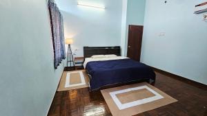 a bedroom with a bed with a blue comforter at La Parshwa Villa Maré in Mahabalipuram
