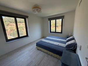 a bedroom with a bed and two windows at Casa la Perla Solo adultos in Béznar