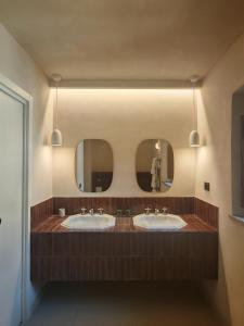 a bathroom with two sinks and two mirrors at Erta Terra Hotel in Mazzolla +65 photos