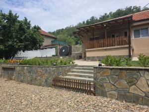 a house with a stone retaining wall and stairs at Seosko domaćinstvo Trajković in Mladenovac