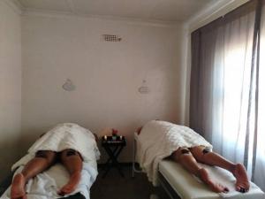 two people laying on beds in a bedroom at Moonlight Guesthouse in Bloemfontein