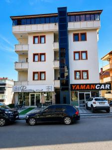 two cars parked in front of a tall building at Blue61 Residence Airport in Pelitli