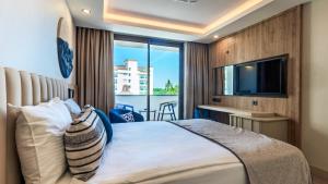 a bedroom with a bed with a television and a balcony at Çenger Blue Collection Hotel Ultra All Inclusive in Manavgat