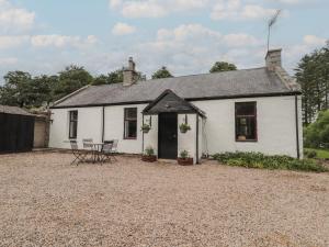 a white cottage with a table and chairs in front of it at Keepers Cottage in Peterhead