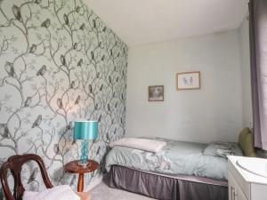 a bedroom with a bed and a table with a lamp at Keepers Cottage in Peterhead