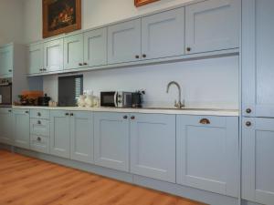 a kitchen with white cabinets and a sink at Farthings, The Old Chapel in St Austell
