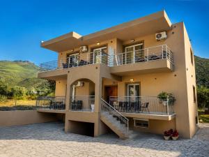 a house with balconies and tables and chairs at Katsanikos Apartments in Prinos