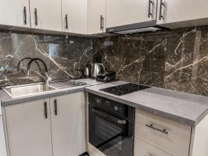 a kitchen with white cabinets and a stove and a sink at Katsanikos Apartments in Prinos +30 photos