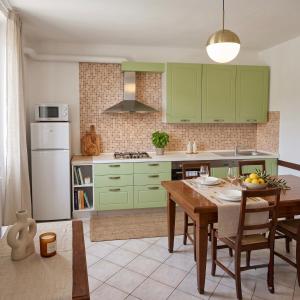 a kitchen with green cabinets and a wooden table at Casa Stella in Sarnano