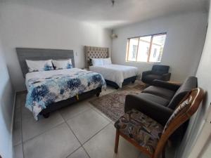 a bedroom with two beds and a chair and a couch at Sintha guest house in Kraaifontein